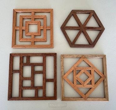 Four wooden geometric wall decorations on a white wall.
