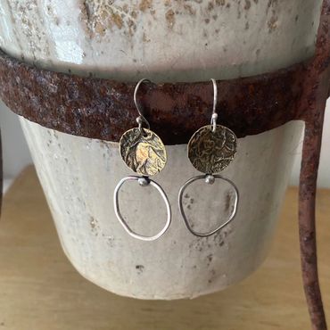 silver earrings hanging on a pot plant stand