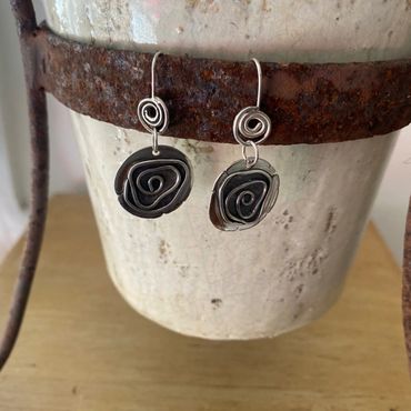 silver earrings hanging on a pot plant stand