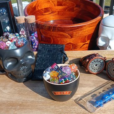 Display of dice. Black skull cup holding dice, a ceramic cup with dice, a tube of blue dice