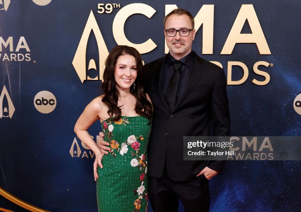 A couple poses on the red carpet at the 59th CMA Awards.