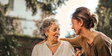Two women sharing a warm, joyful moment outdoors.