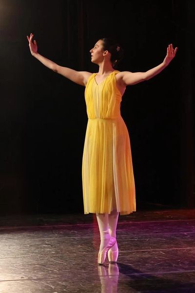 Danseuse en robe jaune sur scène.