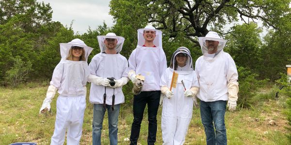 A group of 5 people in beekeeping suits.