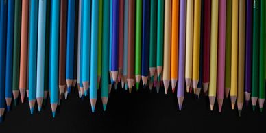 Multiple colored pencils facing down over a black background
