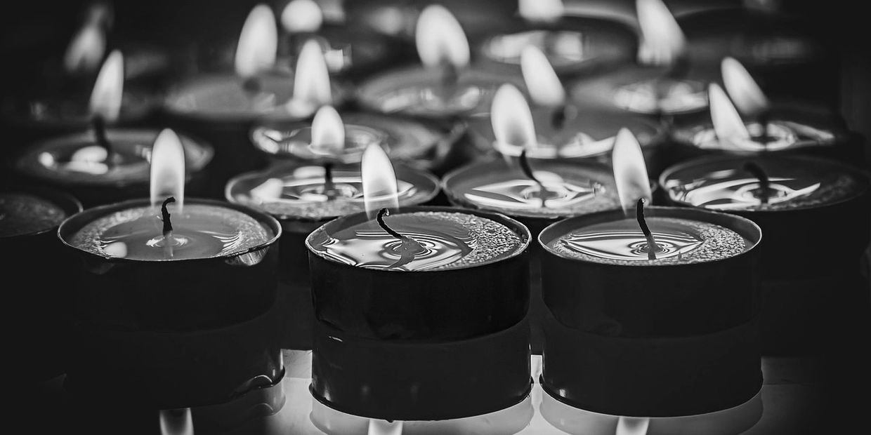 black & white photo of tealight candles lighting up the dark