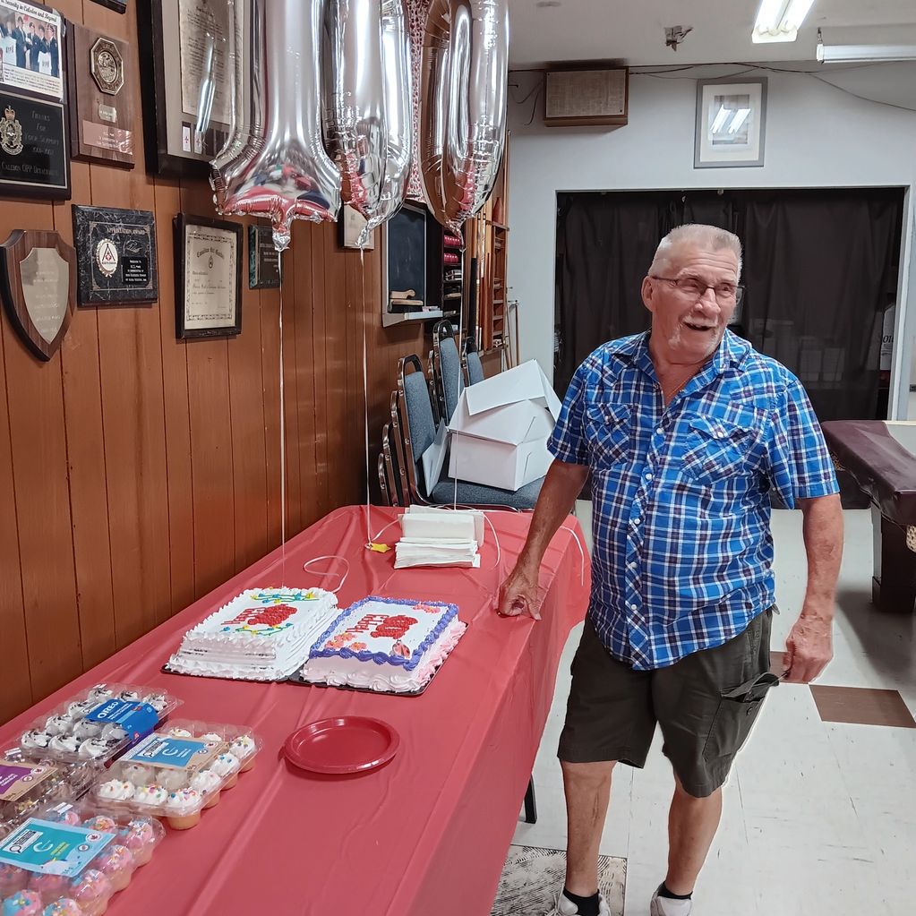 Man celebrating 110th birthday with cakes and balloons.