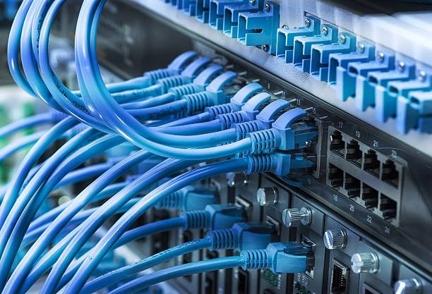 Blue Ethernet cables connected to networking hardware in a data center.