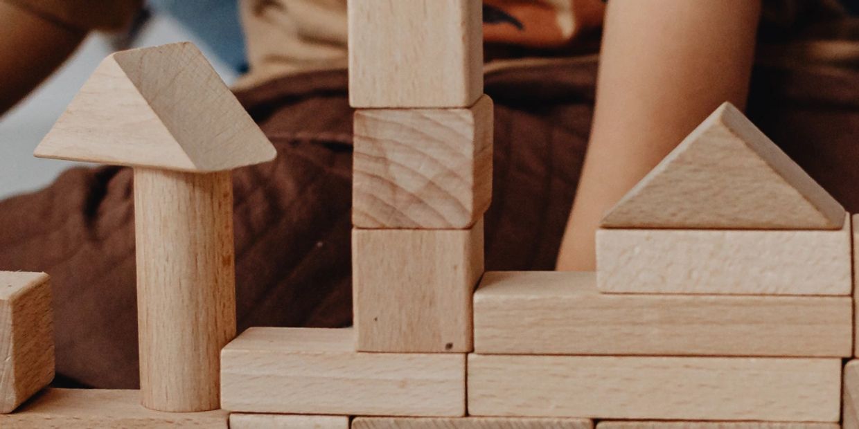 Child playing with wooden building blocks creating a small structure.