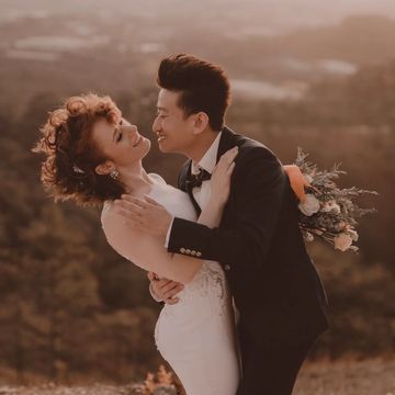 Couple embracing while holding flowers in front of beautiful forest view