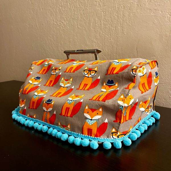 Handmade Perkins Brailler dust cover by Elizabeth using a red fox cartoon fabric with blue trim.