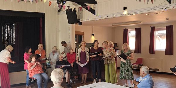 Seniors gathered for a choir rehearsal in a community hall.