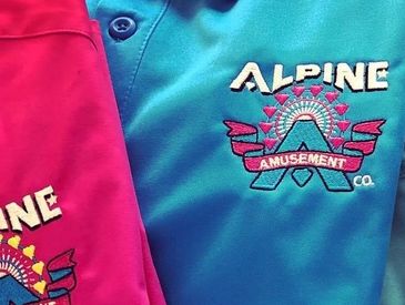 Three colorful Alpine Amusement polo shirts.