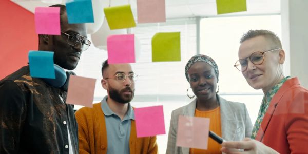 A diverse group brainstorming with colorful sticky notes on glass.