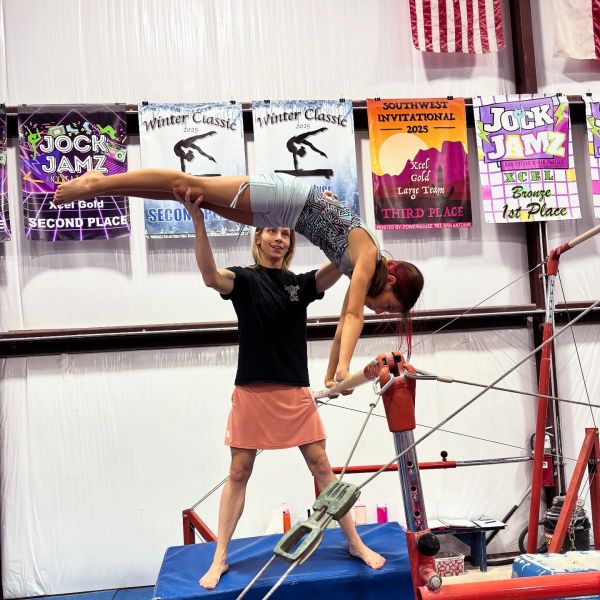 Two women performing a gymnastics balancing act indoors.