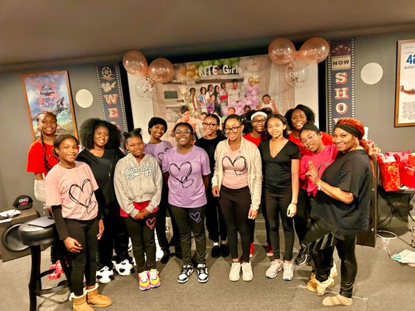 Group of smiling girls and women posing indoors at a decorated event.