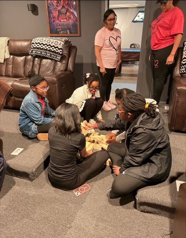 A group of people playing a game with wooden blocks indoors.