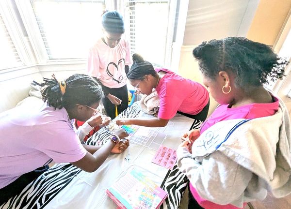 Four girls engaging in a creative activity around a table in a bright room.