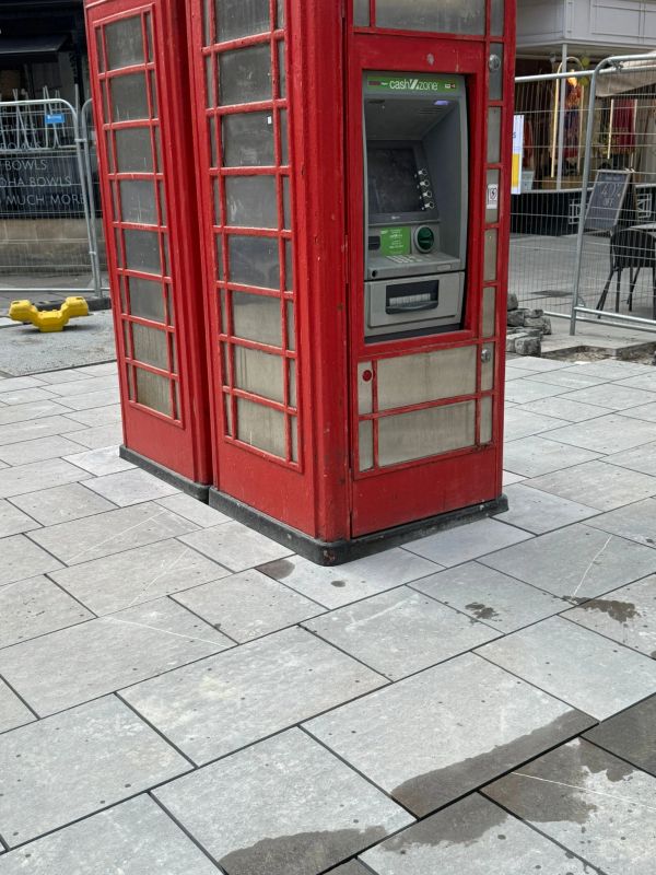 Red phone booth with an ATM machine inside.