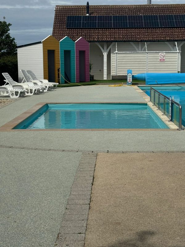 Empty pool area with colorful changing huts and white lounge chairs.