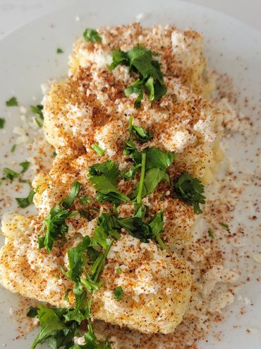 Cauliflower seasoned with spices and garnished with fresh herbs on a white plate.