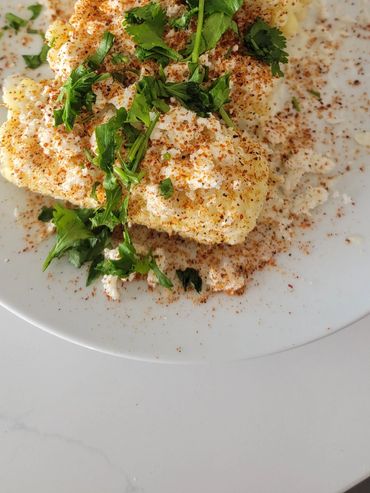 Cauliflower seasoned with spices and garnished with fresh herbs on a white plate.