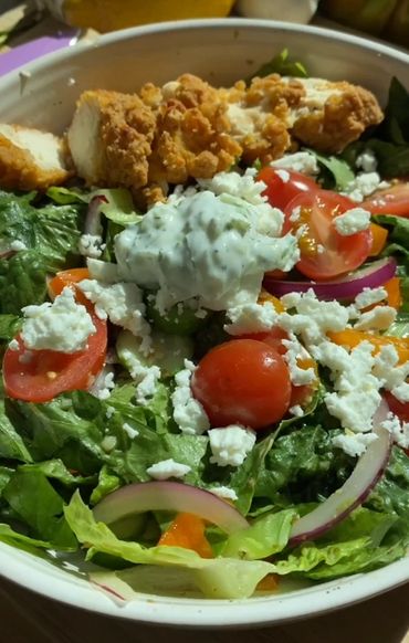 Fresh salad with cherry tomatoes, feta cheese, red onions, and crispy chicken strips.