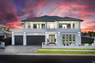 Modern two-story house at sunset with dramatic sky.