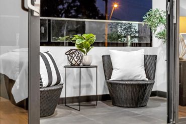 Cozy balcony seating with cushions and plants at night.