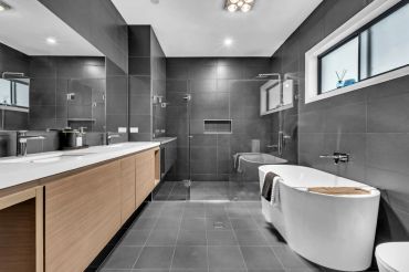 Modern bathroom with gray tiles and wooden vanity.