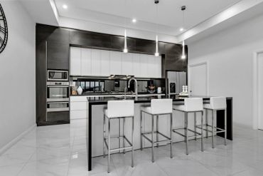 Modern kitchen with black and white design and bar stools.