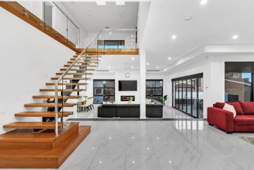 Modern living room with floating staircase and red sofa.