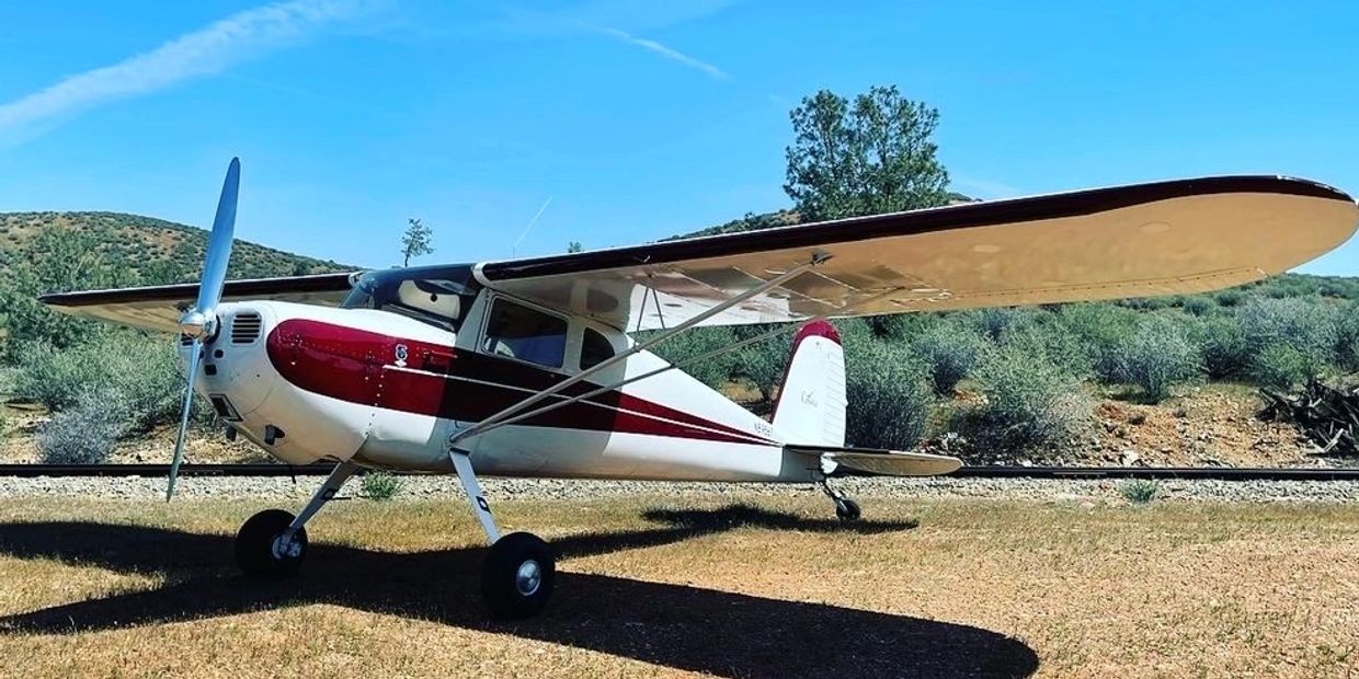 Small vintage single-engine airplane parked on grass.