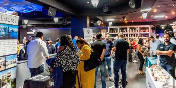 People socializing and exploring booths at an indoor event.