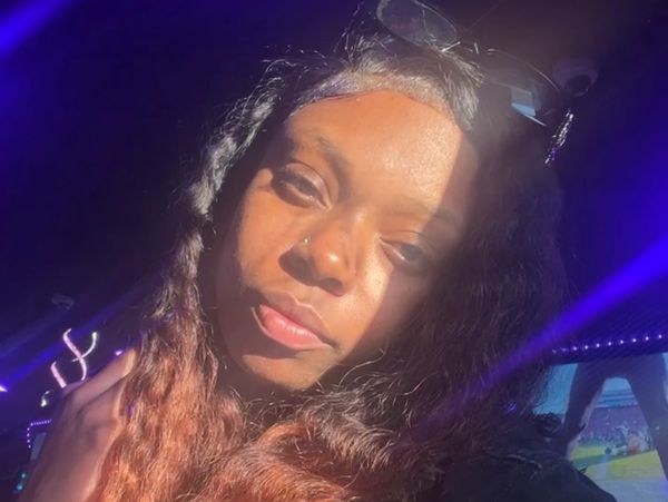 Woman with long hair illuminated by sunlight and purple light.