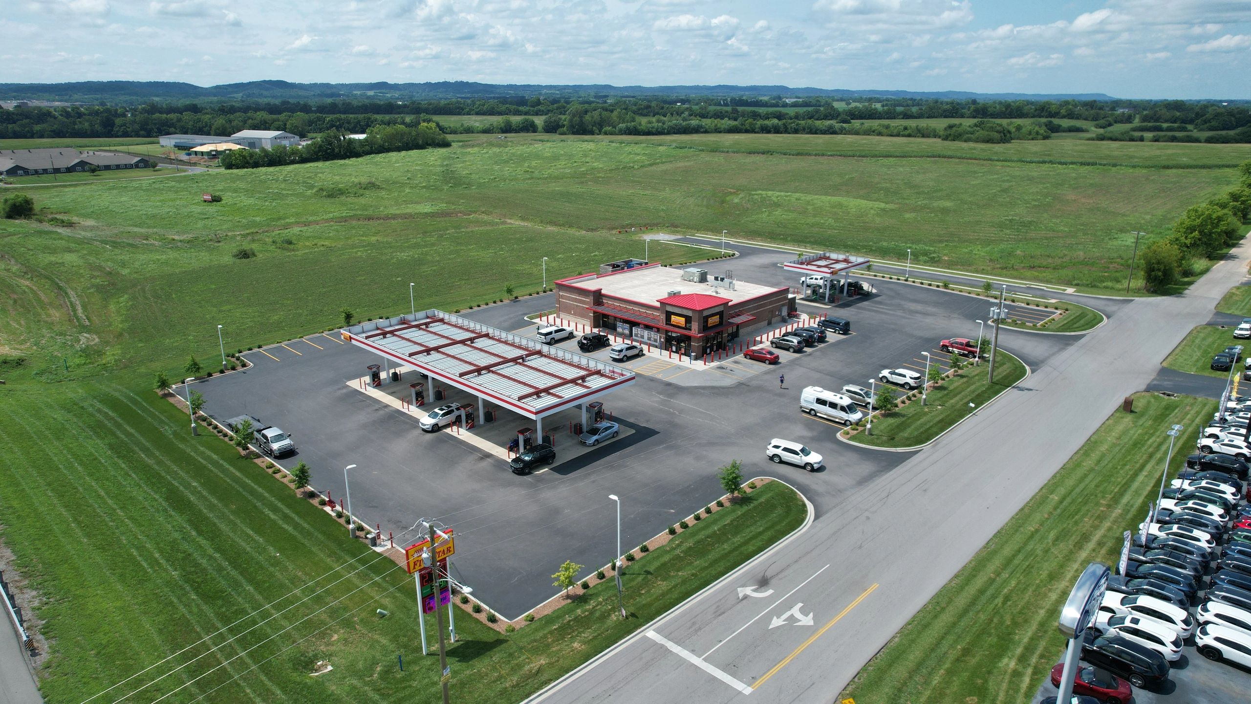 A gas station with convenience store amidst green fields.