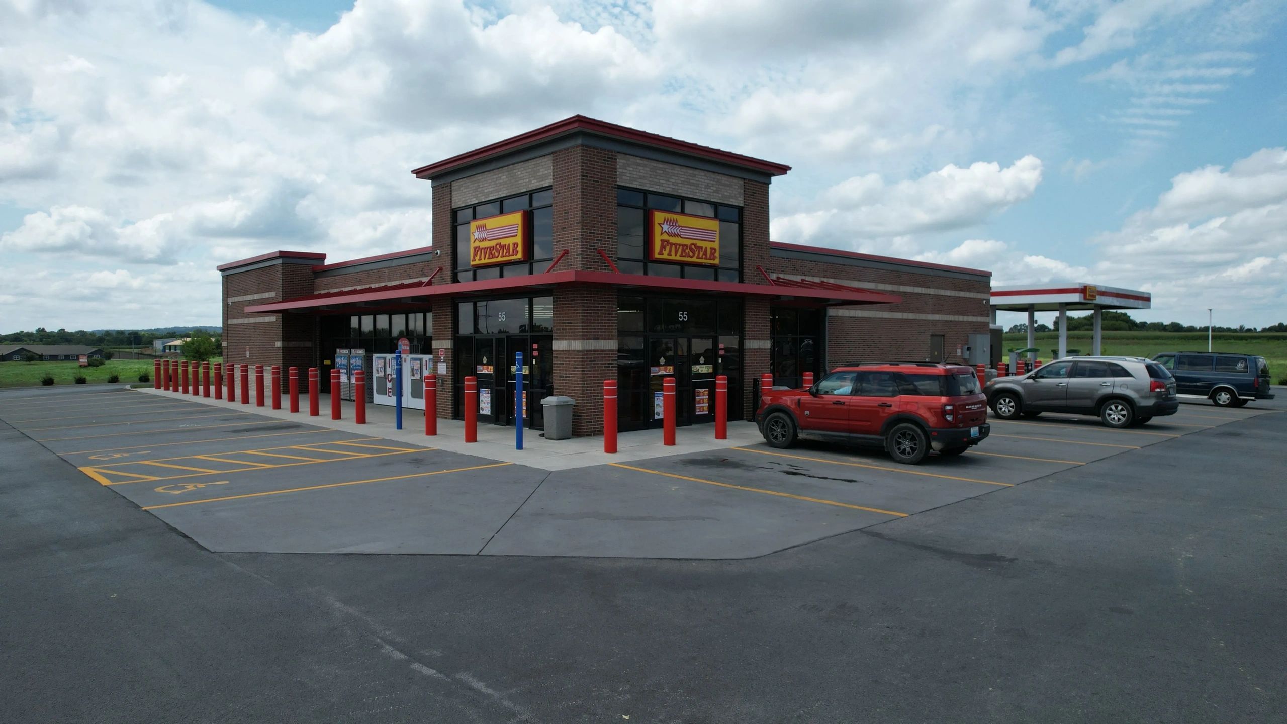 Convenience store with parking and cloudy sky.