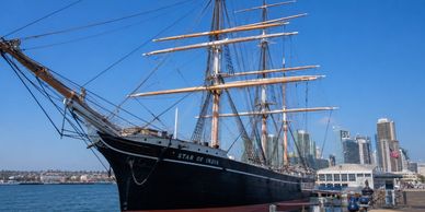 Historic tall ship Star of India docked by the city waterfront.