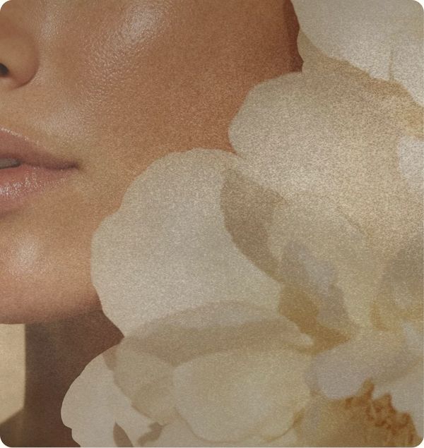Close-up of a woman's face with soft light and white flowers.