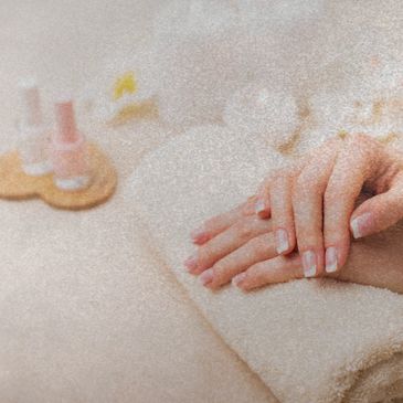 Mãos de pele clara apoiadas em toalha branca, mostrando as unhas feitas com os esmaltes naturais, se