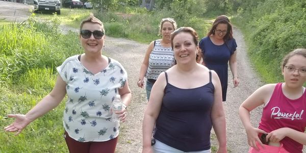 A group of five women walking outdoors on a sunny day.