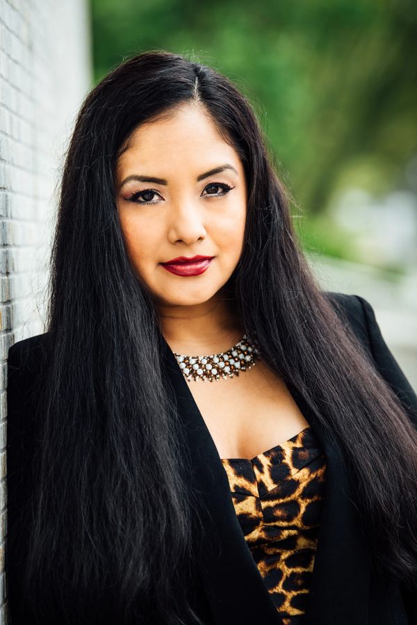 Confident woman with long hair wearing leopard print and black jacket.