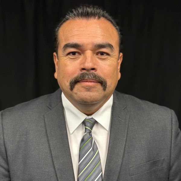Man in gray suit and striped tie with mustache.