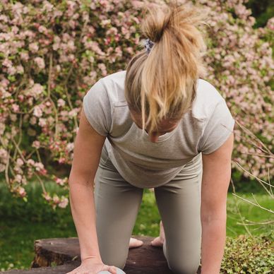 Woman kneeling towards the camera with her hand placed on a ball.