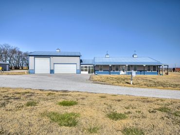 Blue and white ranch-style house with large garage and clear sky.