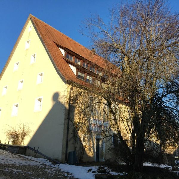 ein Seminarhaus mit dem blauen Himmel im Hintergrund und etwas Schnee auf der Erde
