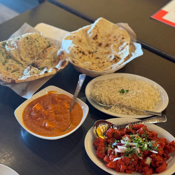 Indian meal with naan, rice, curry, and tandoori chicken served on a table.