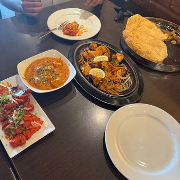 Indian cuisine spread with curry, rice, naan bread in steel bowls

