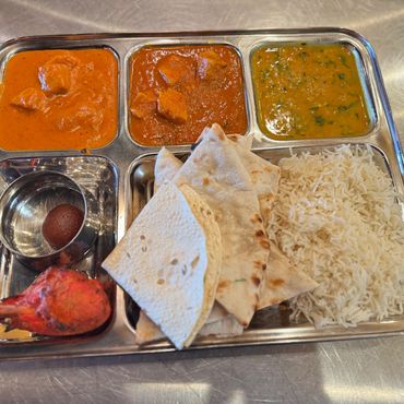 Colorful Indian meal: rice, curry, naan in metal bowls on table

