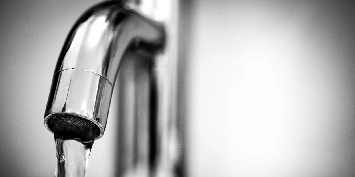 A kitchen faucet with running water, representing residential water quality and well water testing.